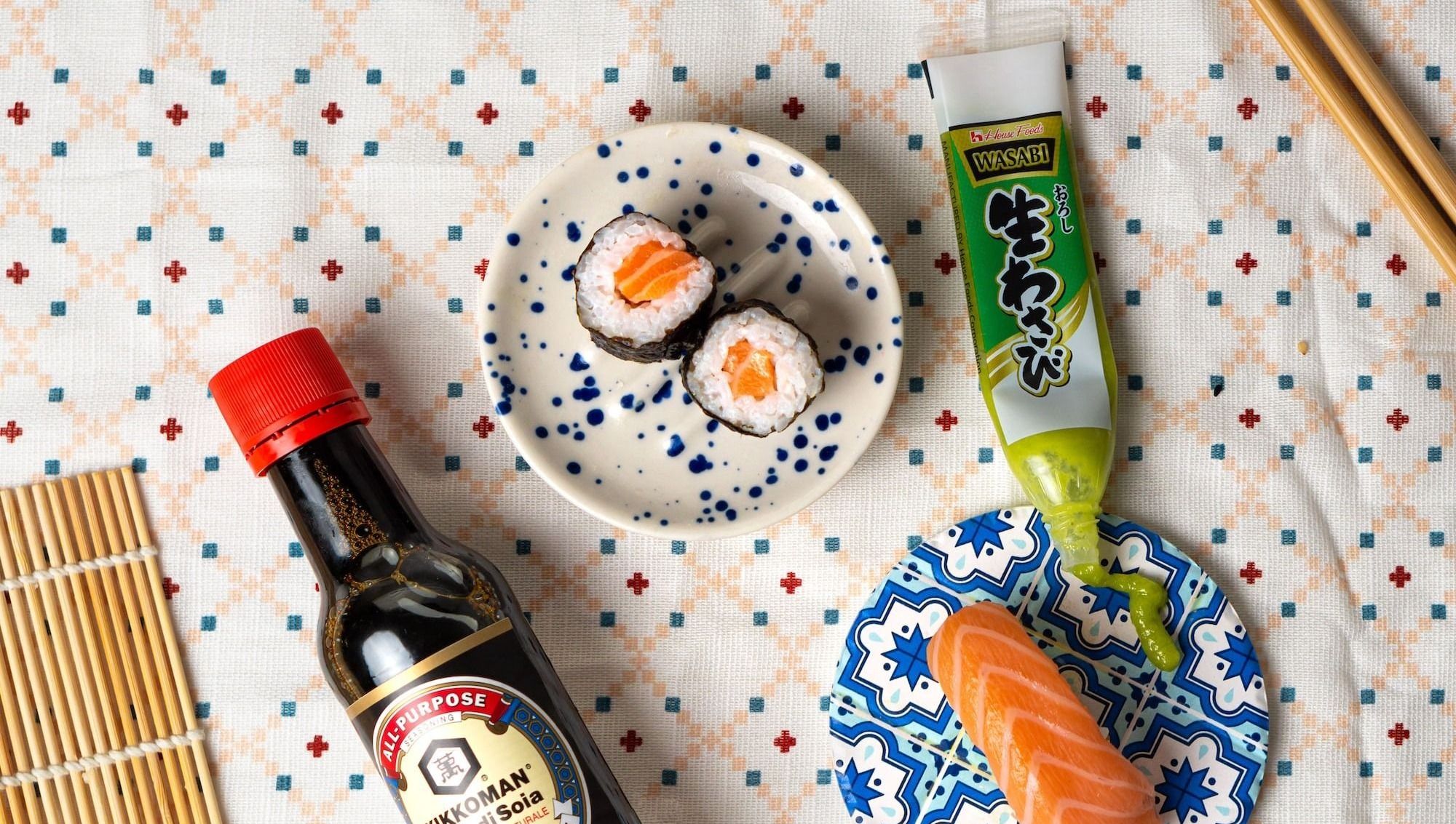 a table topped with a plate of sushi and a bottle of sauce