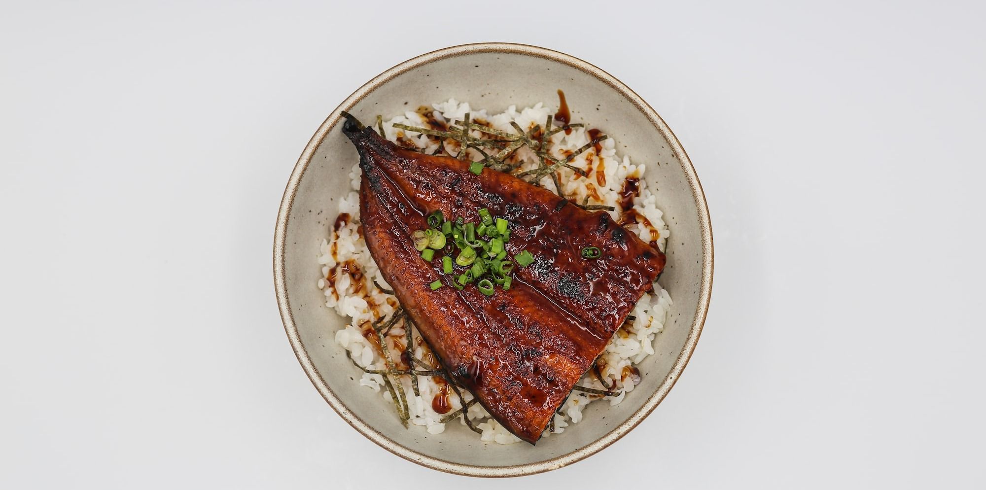 a white bowl topped with Unagi and rice