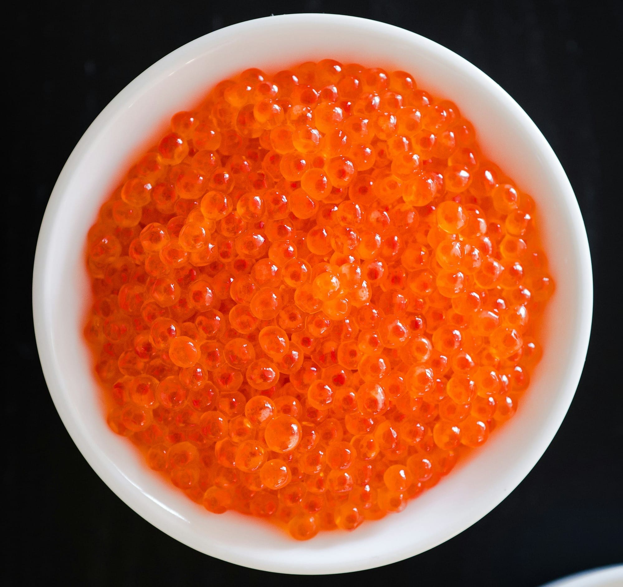 A white bowl filled with Ikura, Salmon Roe